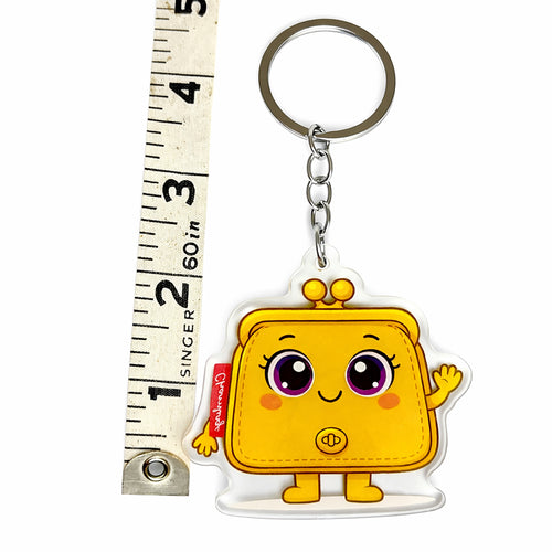 Yellow cartoon wallet keychain with a ruler for scale on a white background