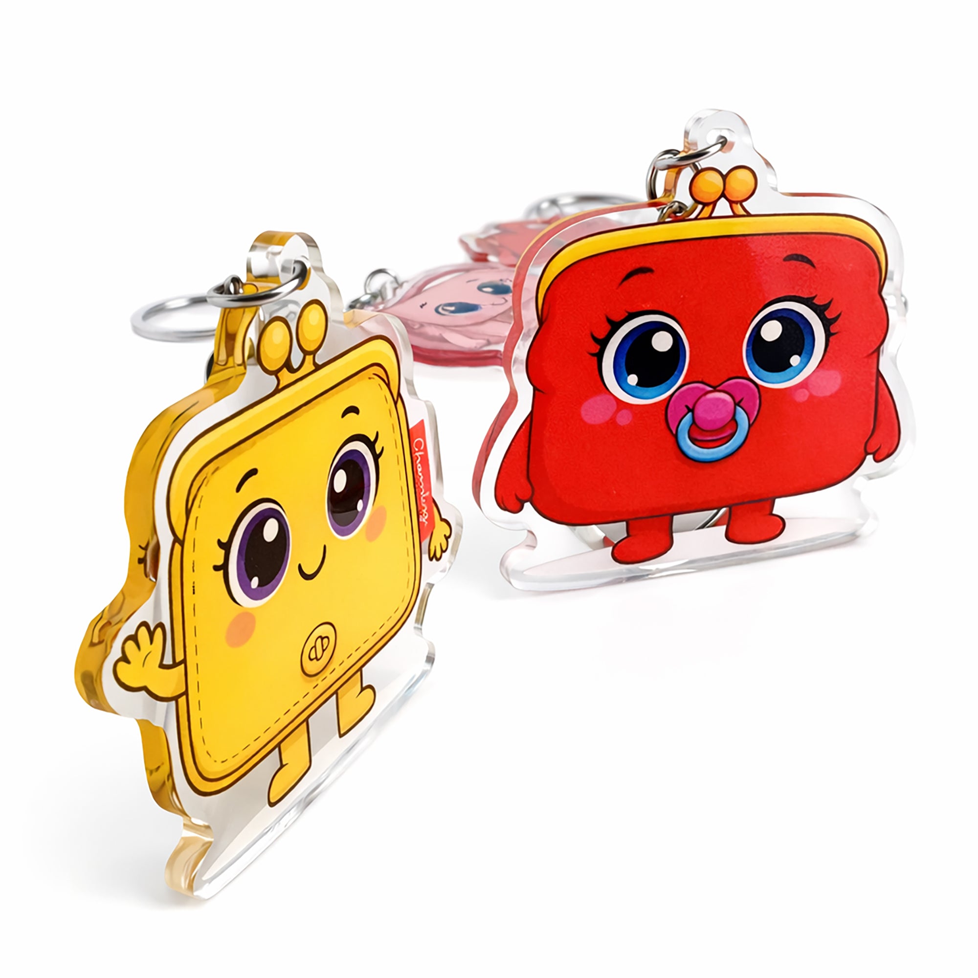 Two cartoon character keychains, one yellow and one red with a pacifier, on a white background.