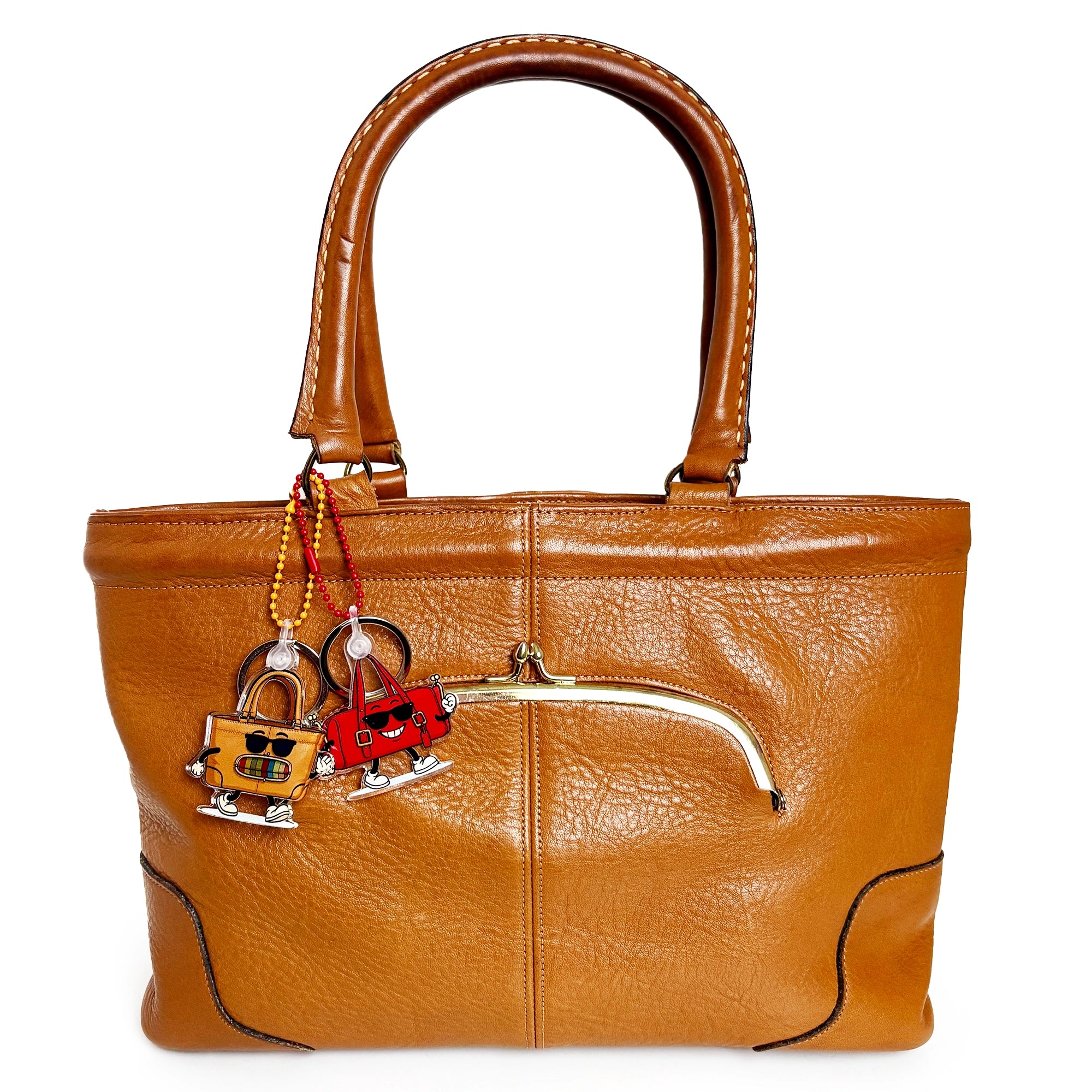 Brown leather handbag with decorative charms on a white background