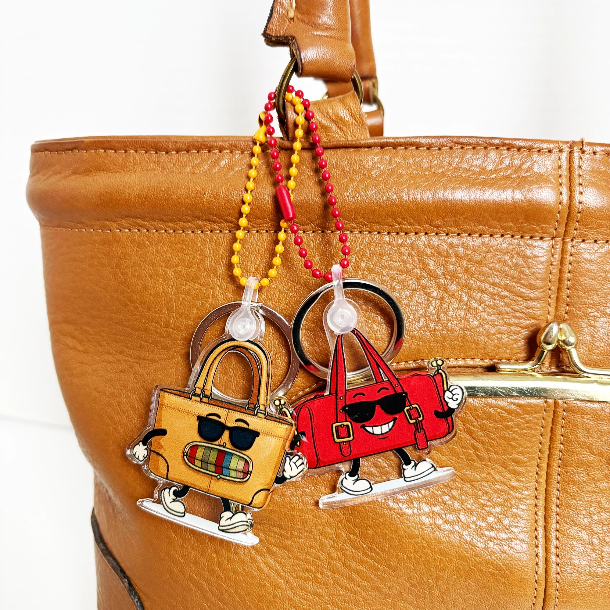 Two cartoon-style keychains attached to a brown leather bag.