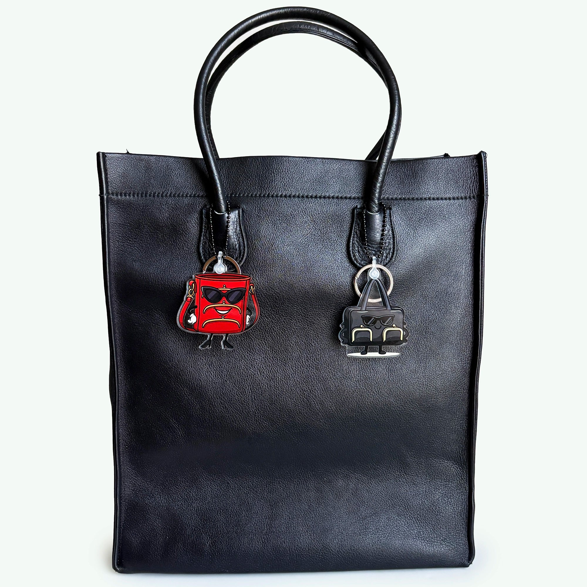 Black handbag with a red and silver charm on a white background