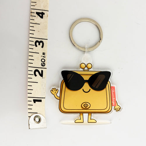 Bag Charm Keychain shaped like a cartoon handbag with sunglasses, next to a ruler for scale.
