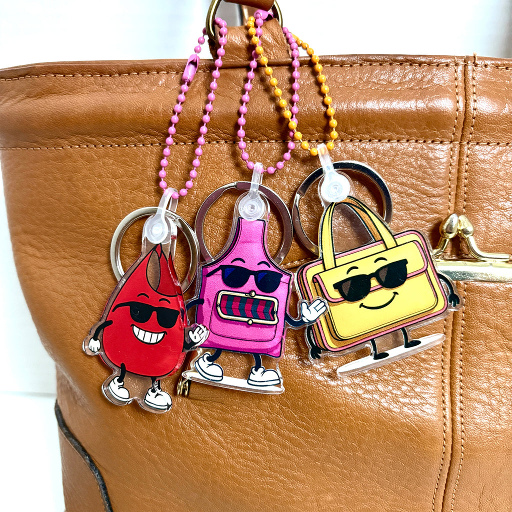 Charmlingz Slingy, BB and Ms Saffe bag charm key chain close up on vintage hand bag