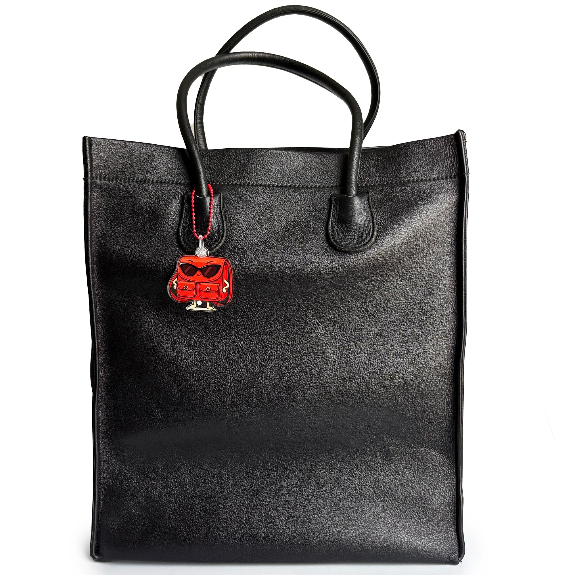 Black tote bag with a red and black Charmlingz Posty bag charm keyring on a white background