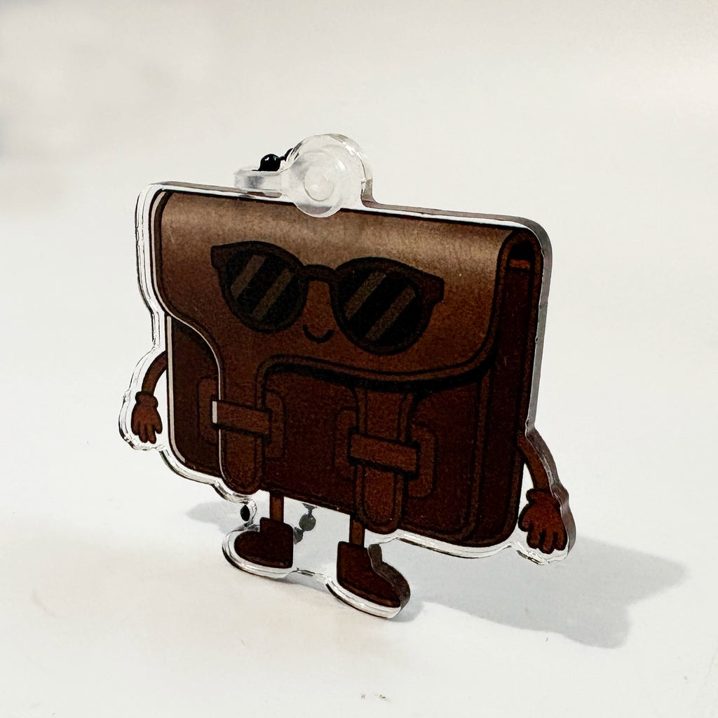 Brown purse-shaped character bag charm with sunglasses on a white background