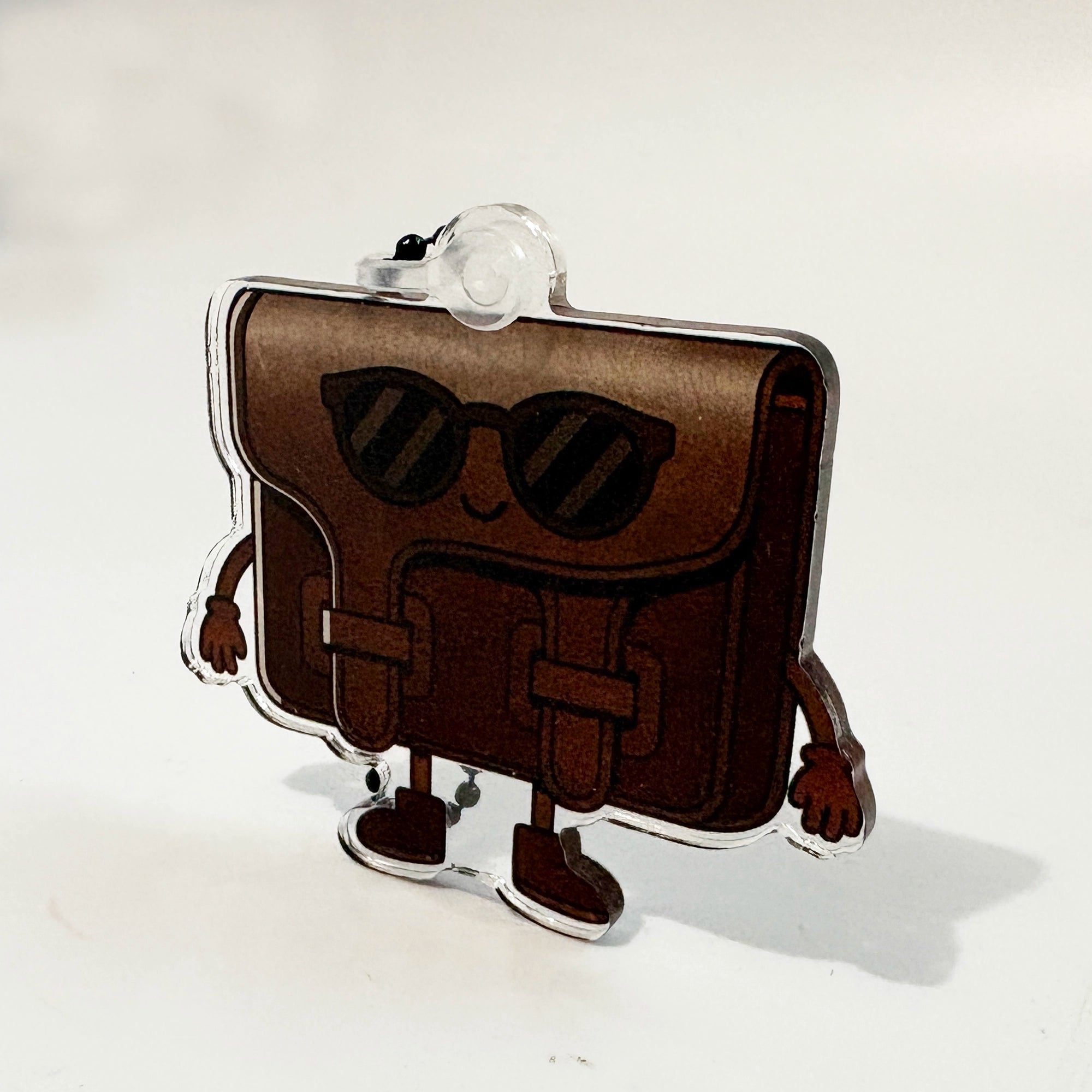 Brown purse-shaped character bag charm with sunglasses on a white background