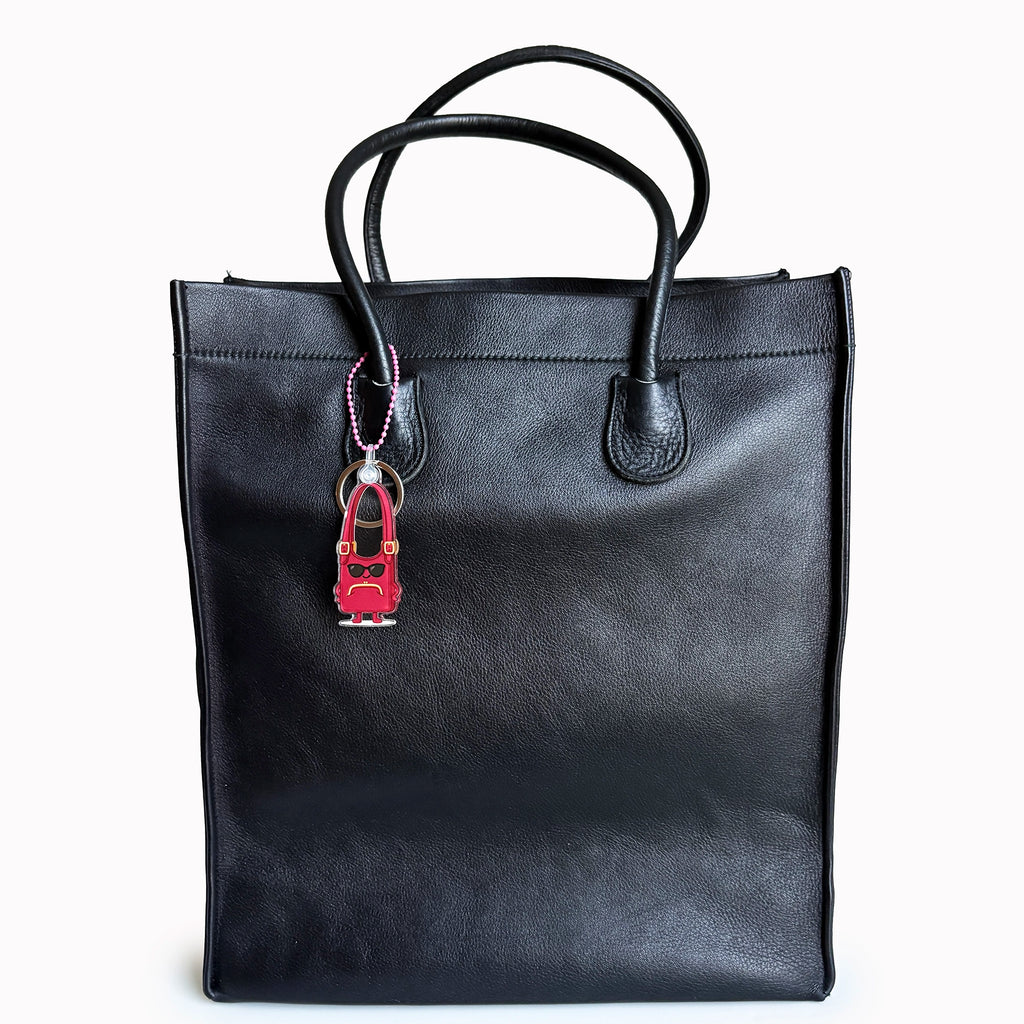Black tote bag with a red and black keychain on a white background