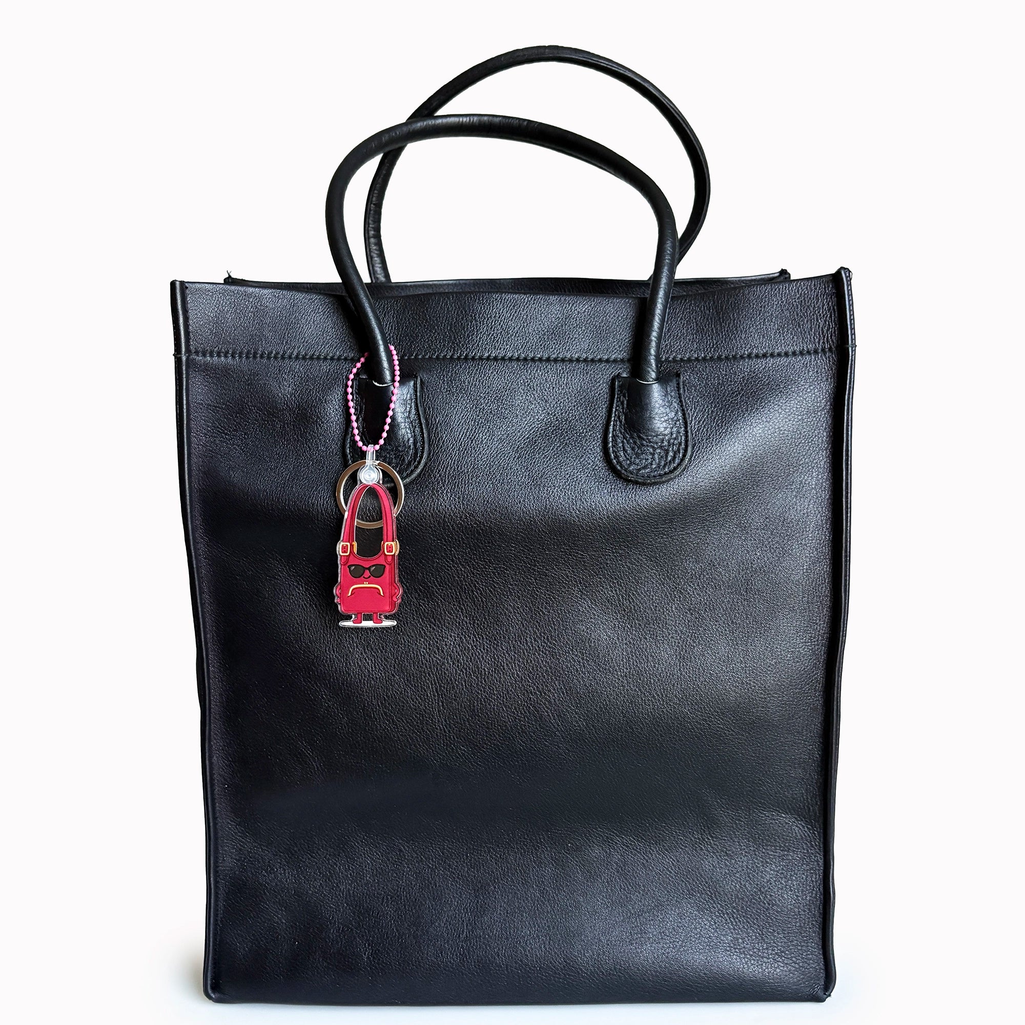 Black tote bag with a red and black keychain on a white background