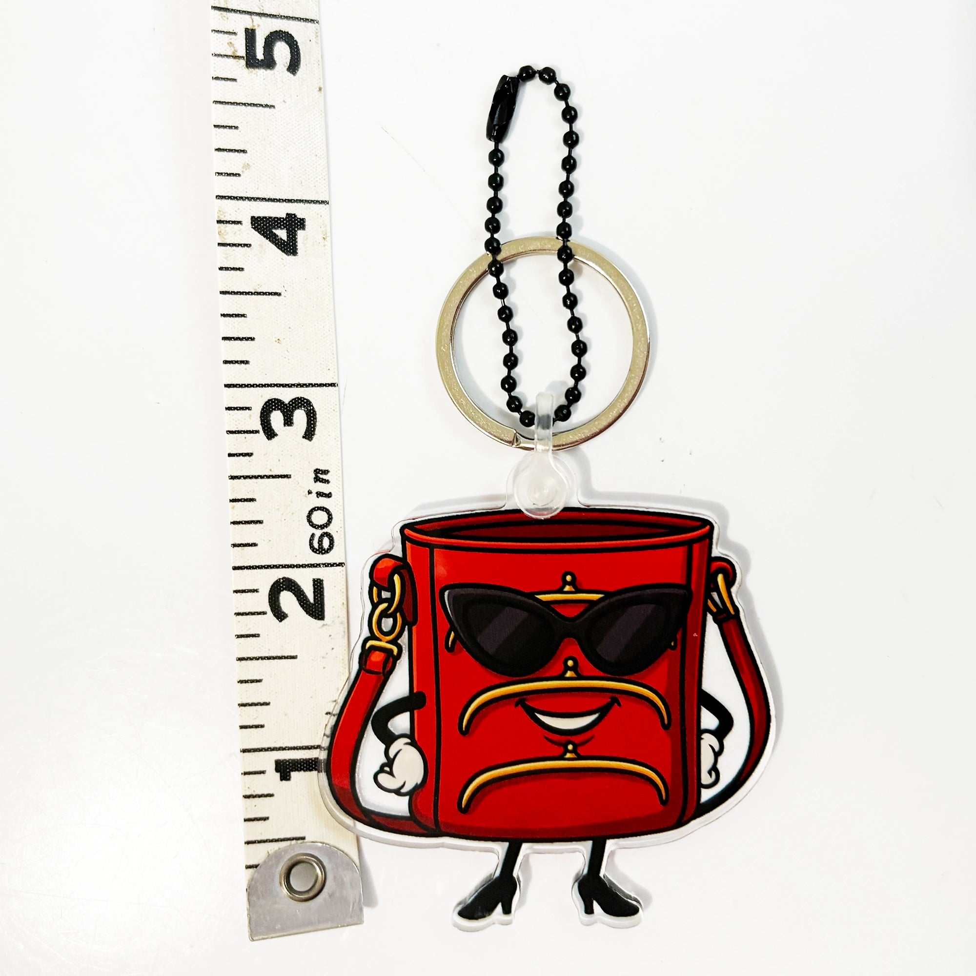 TriFramea Red bucket purse character keychain bag charm with sunglasses next to a ruler for scale.