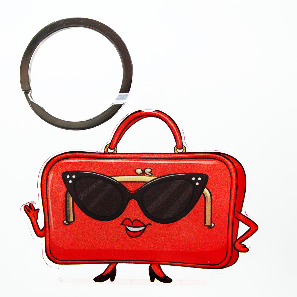 Red handbag keychain with sunglasses and a smiling mouth on a white background