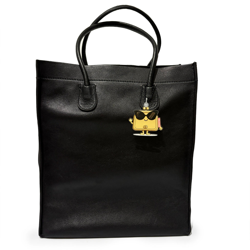 Black tote bag with a gold and black charm on a white background