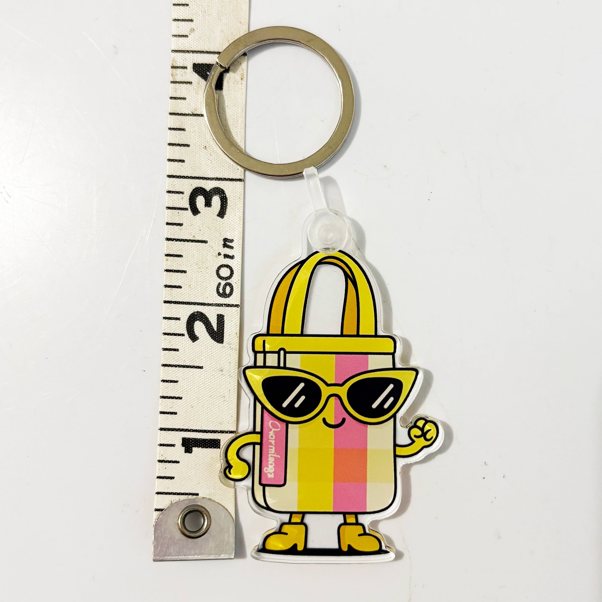 Keychain bag charm with a cartoon-style handbag character wearing sunglasses, standing next to a ruler for scale.