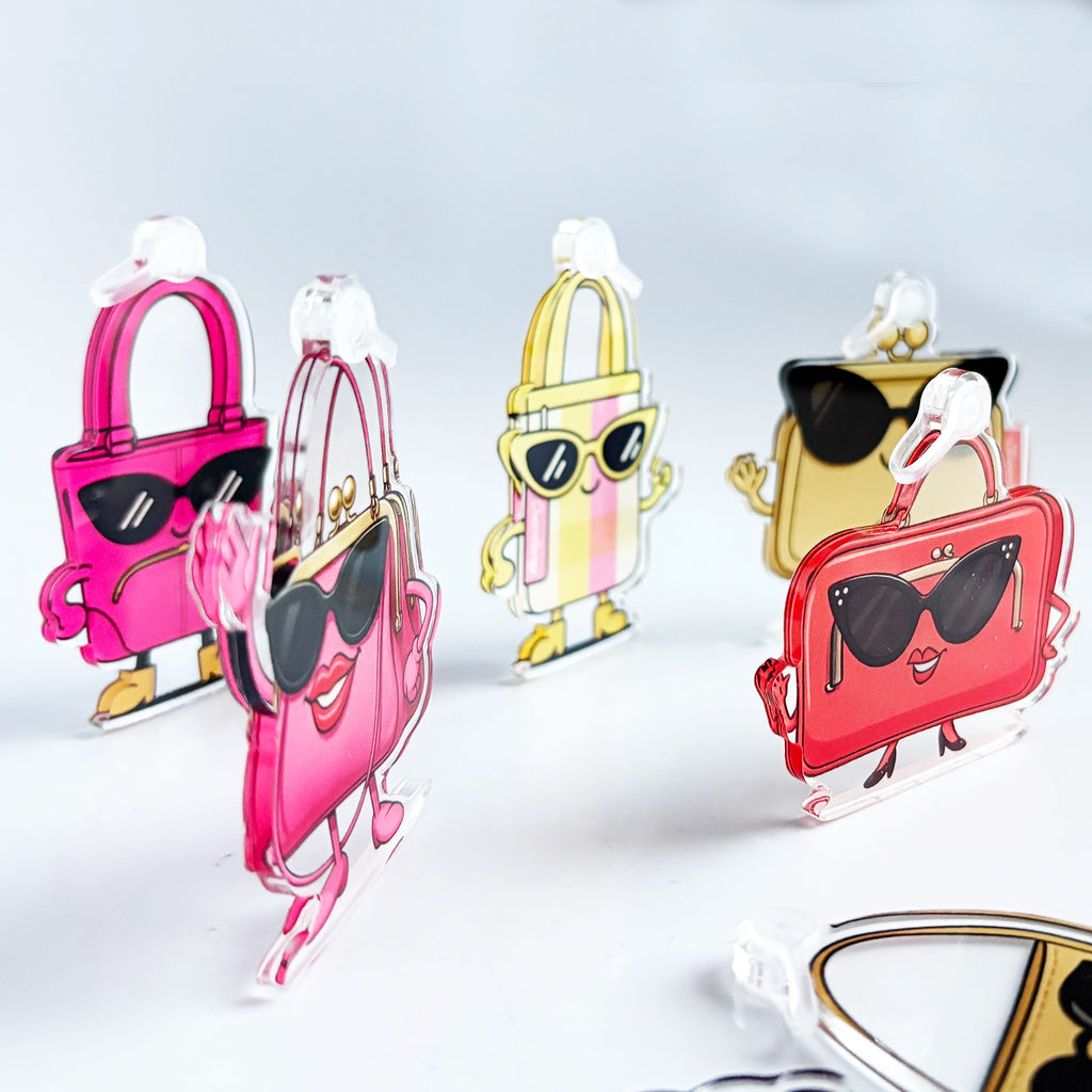 Colorful handbag-shaped keychains with cartoon faces on a light gray background