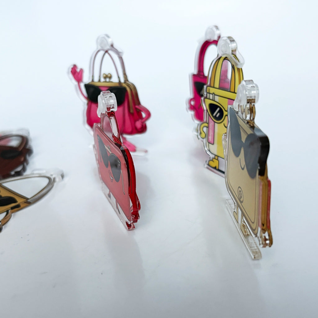 Colorful Charmlingz handbag-shaped keychains charms with sunglasses on a white background, shown from side to show width.