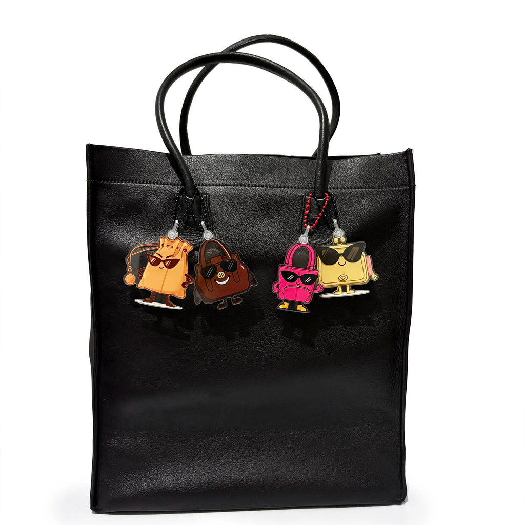 Black tote bag with cartoon character keychains on a white background
