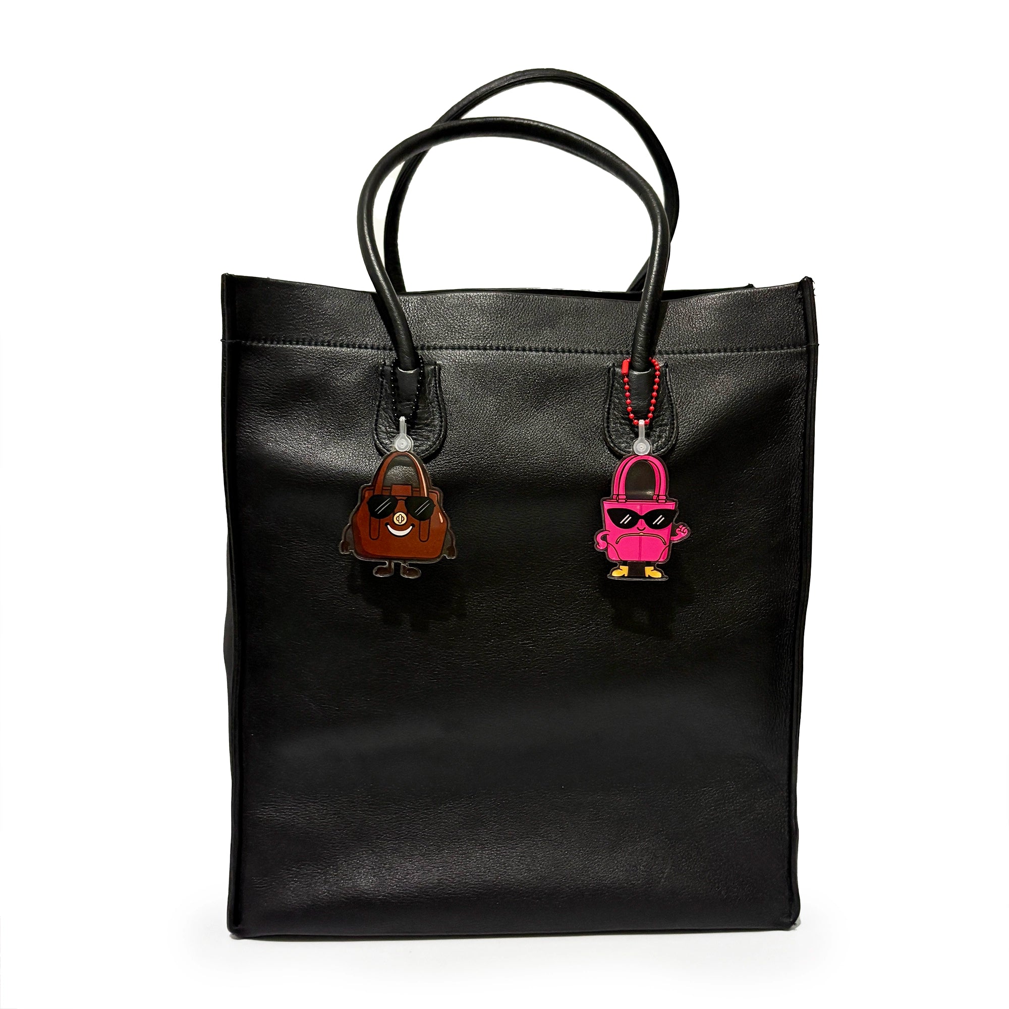 Black leather tote bag with two keychains on a white background