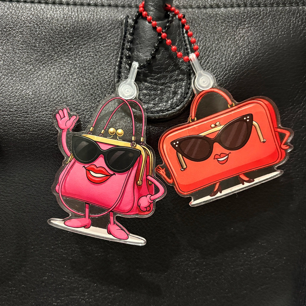 Two Charmlingz cartoon-style handbag charms on a black background