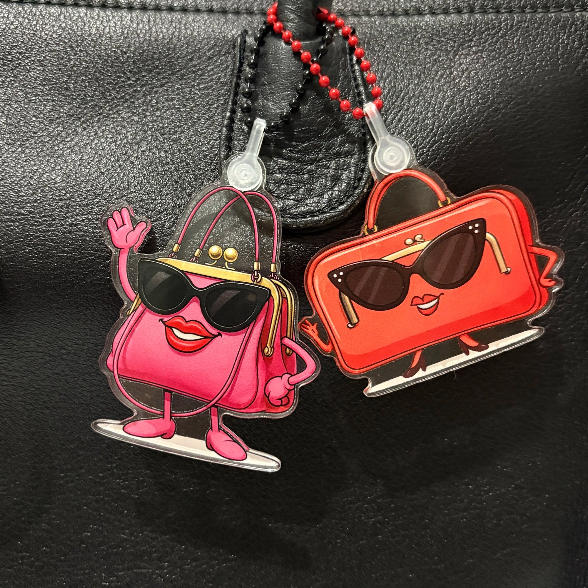 Two Charmlingz cartoon-style handbag charms on a black background
