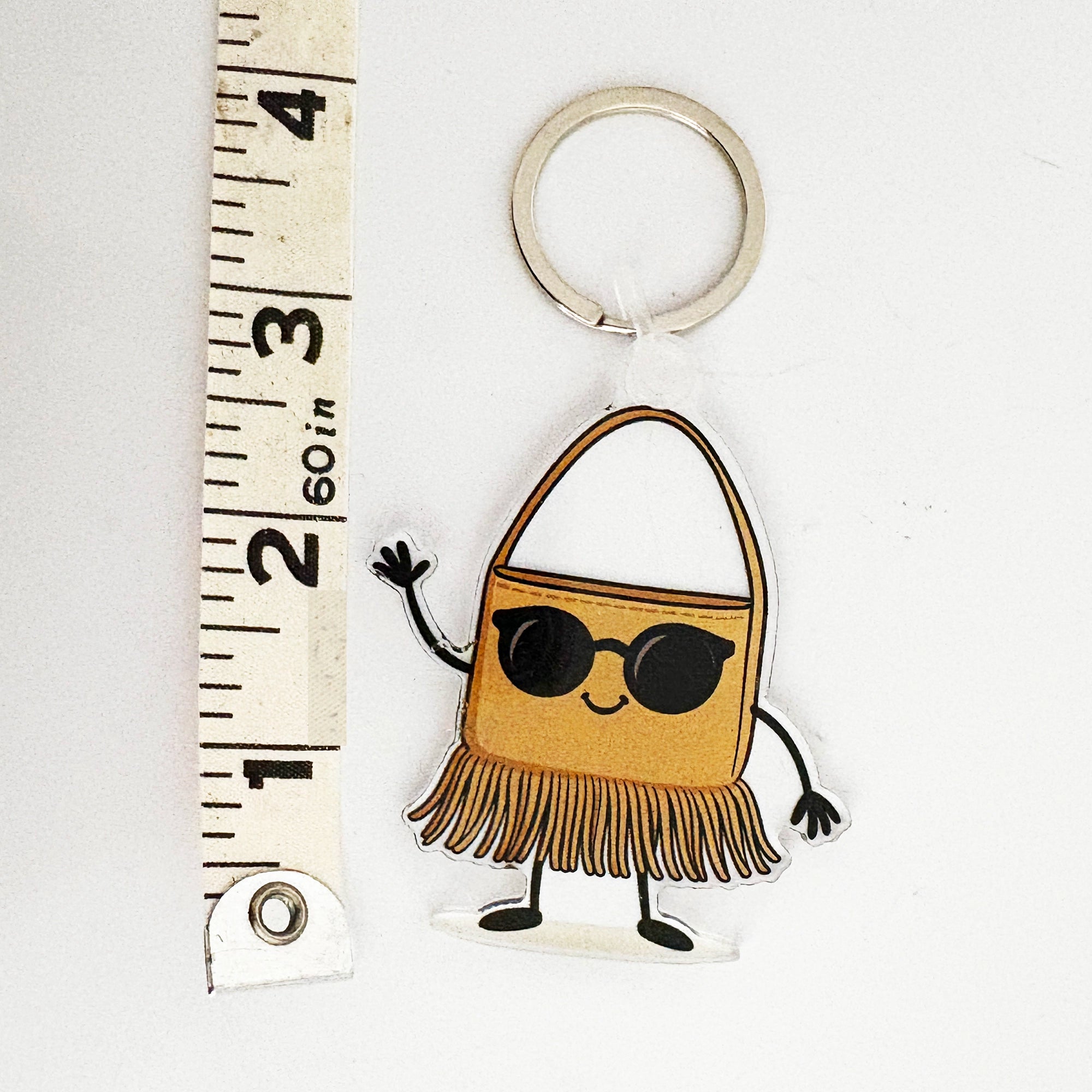 Keychain bag charm shaped like a handbag with sunglasses, standing next to a ruler for scale.