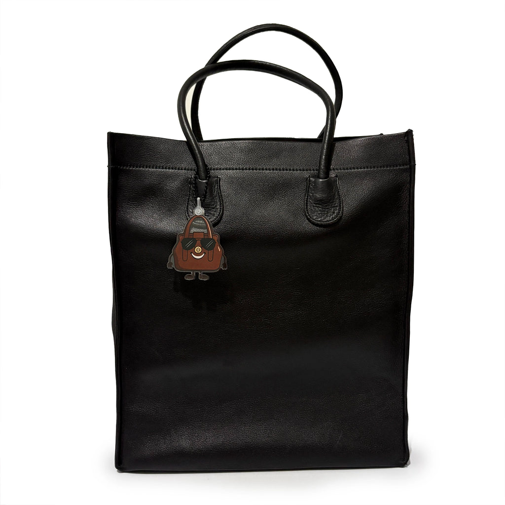 Black leather tote bag with a small brown bag charm on a white background