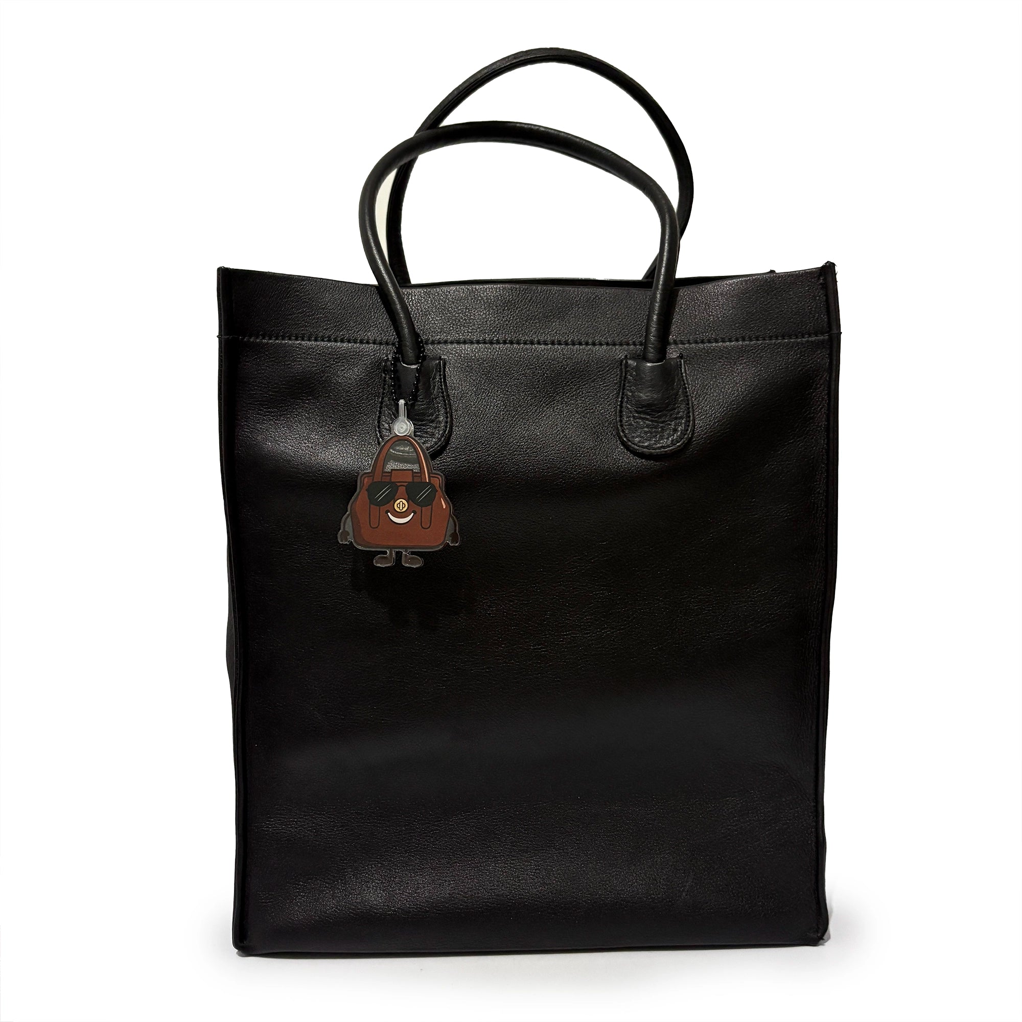 Black leather tote bag with a small brown bag charm on a white background