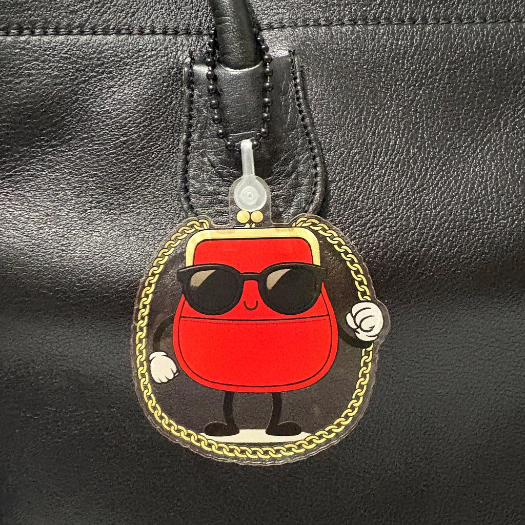 Red handbag shaped bag charm with sunglasses on a black leather surface