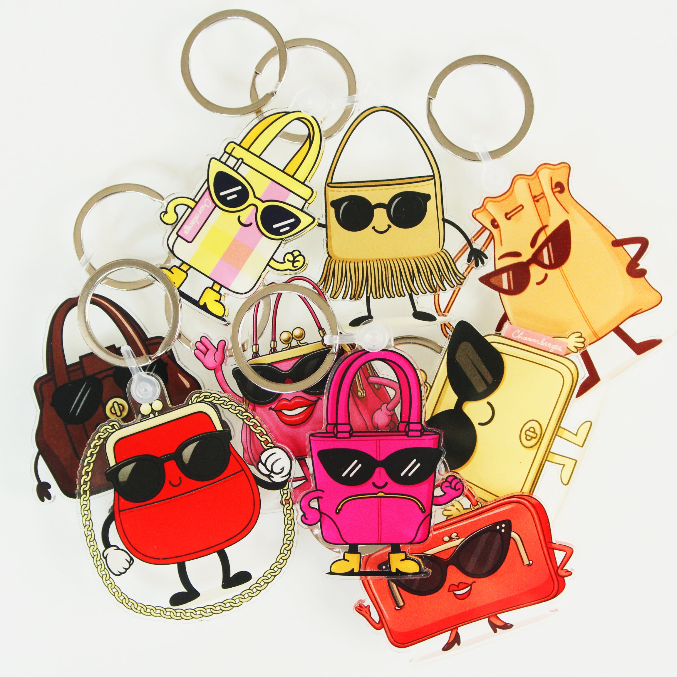 Colorful cartoon-style keychains shaped like bags with sunglasses on a white background