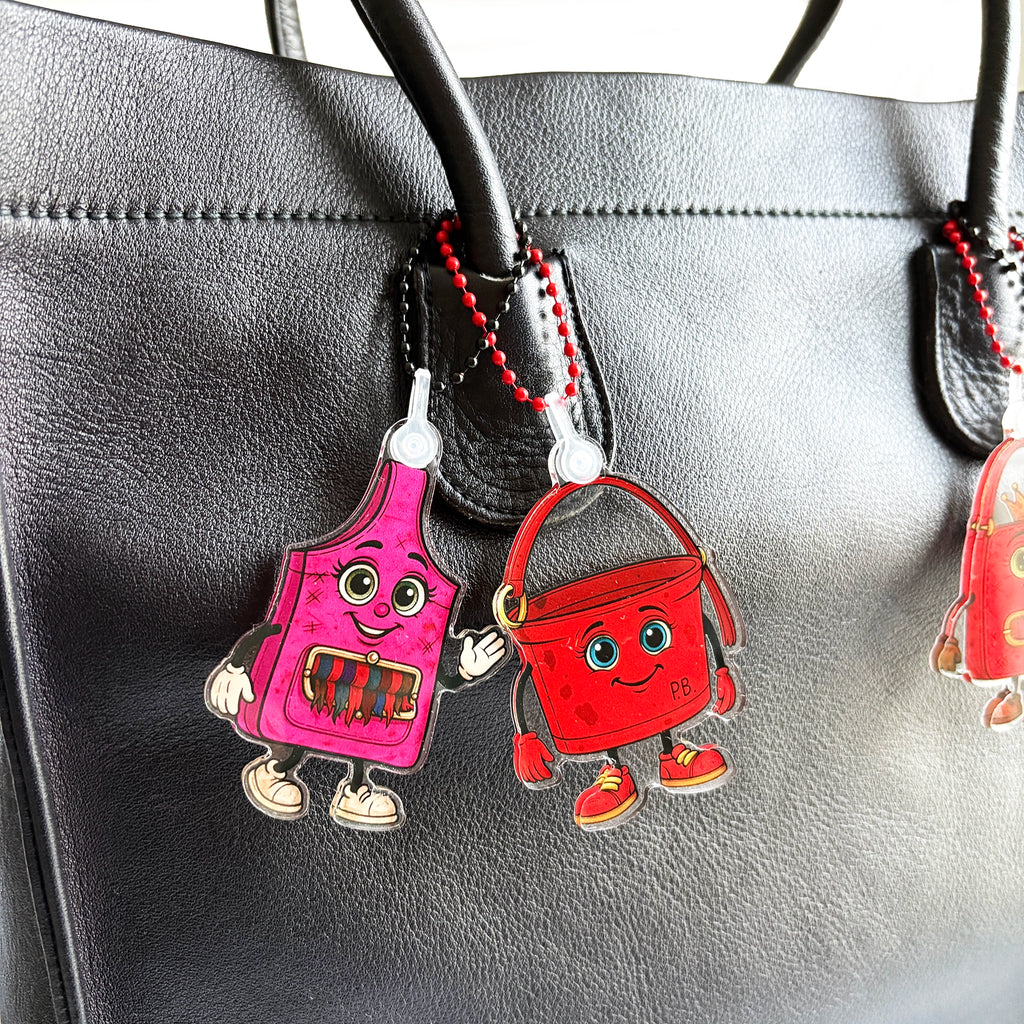Close up styled on vintage handbag showing ReLuvable Slingy bag charm and ReLuvable PB bag charm